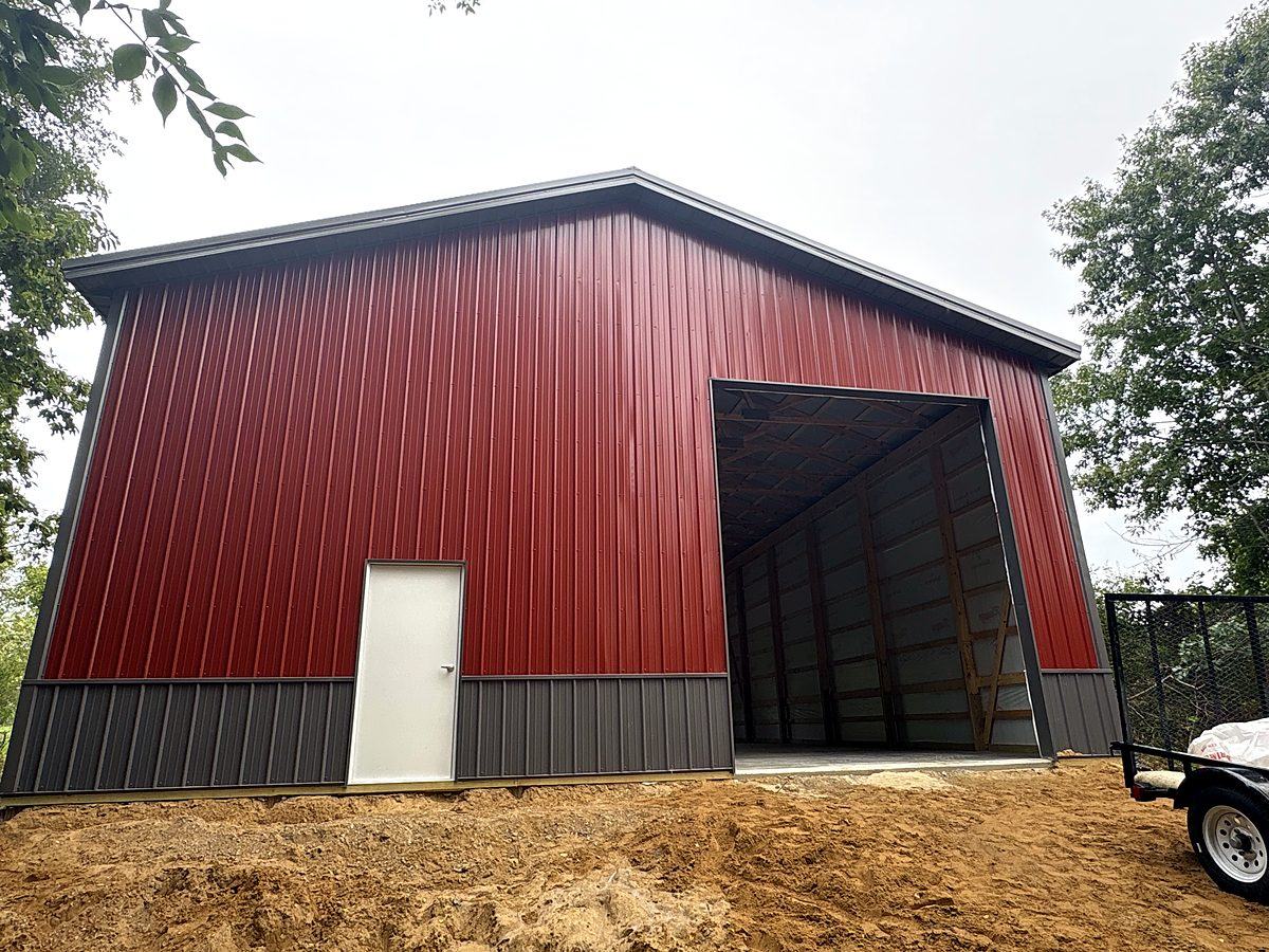Red pole barn with large open door and white walk door