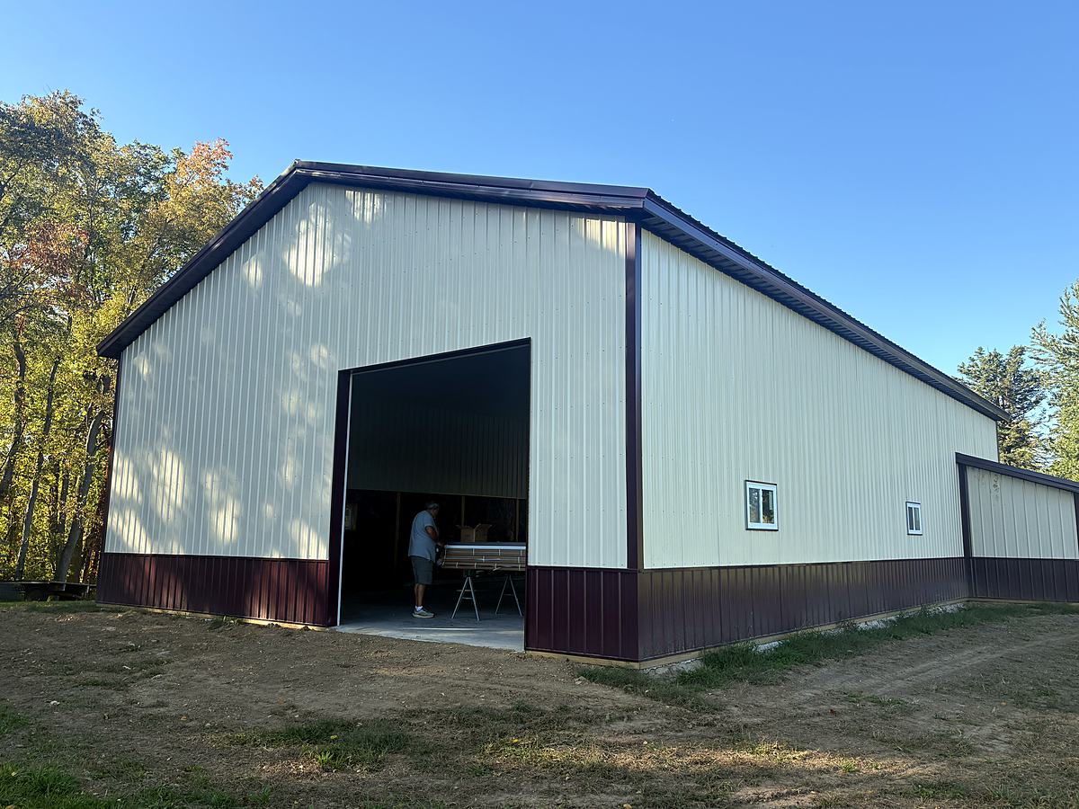 Cream and burgundy post frame shop with large door opening