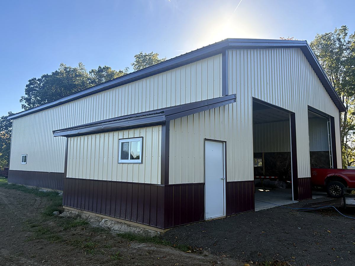 Cream and burgundy pole barn with lean-to, two large door openings and walk door