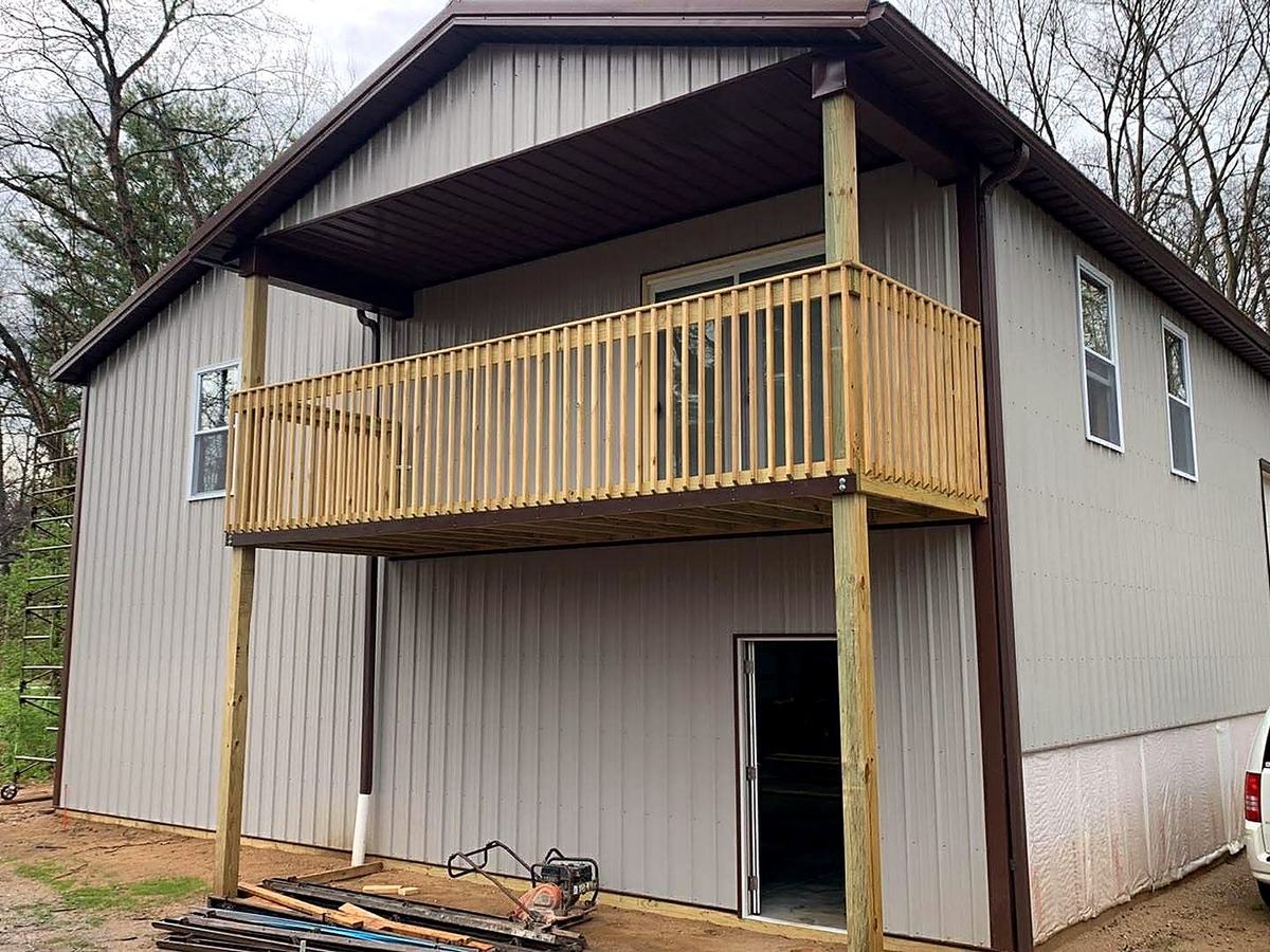 Two-story post frame building with covered balcony and lean-to roof