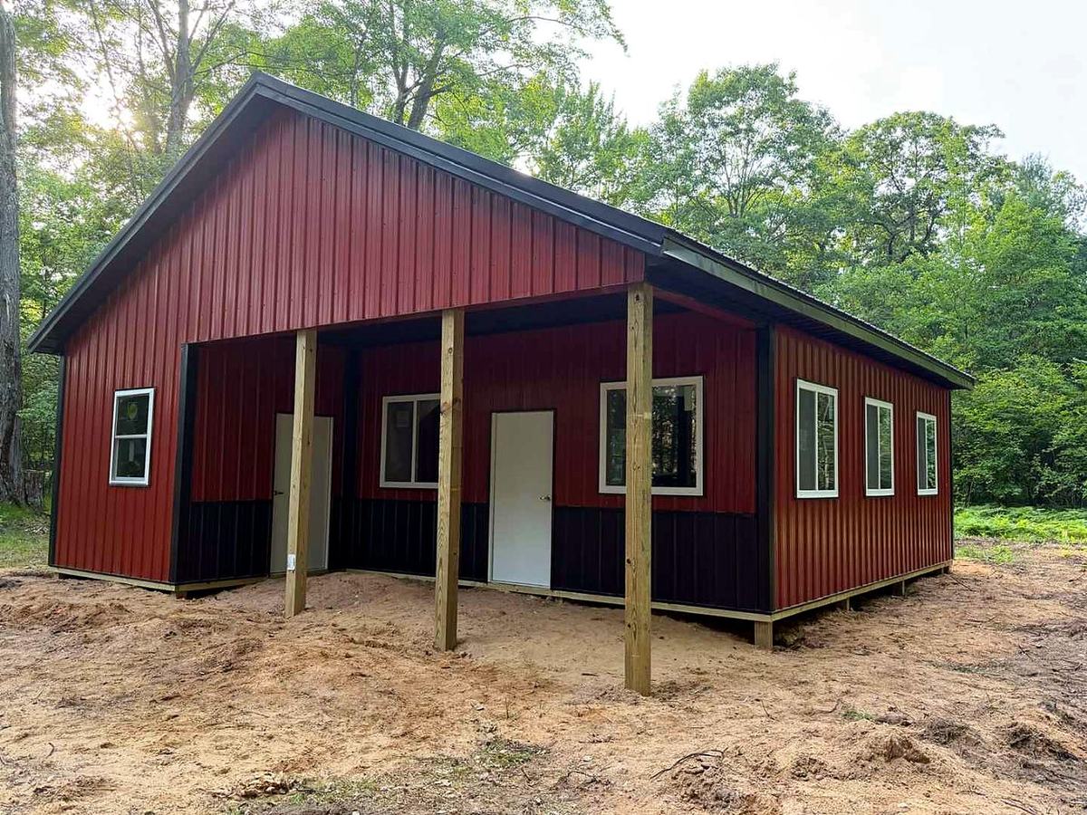 Red pole barn with black wainscot and covered front porch